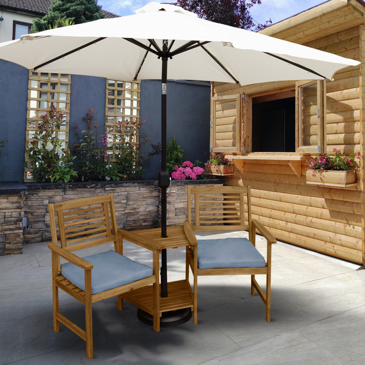 Buiten loveseat van lichtbruin hout met grijze kussens, geplaatst onder een grote parasol in een sfeervolle tuinsetting