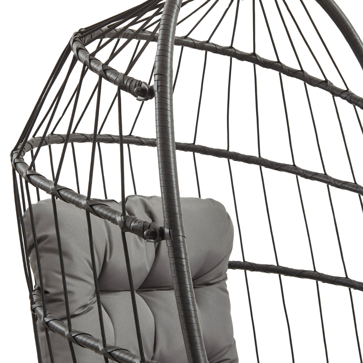 Zwart rotan hangstoel met een moderne, open structuur en een comfortabele grijze kussen voor extra zitcomfort