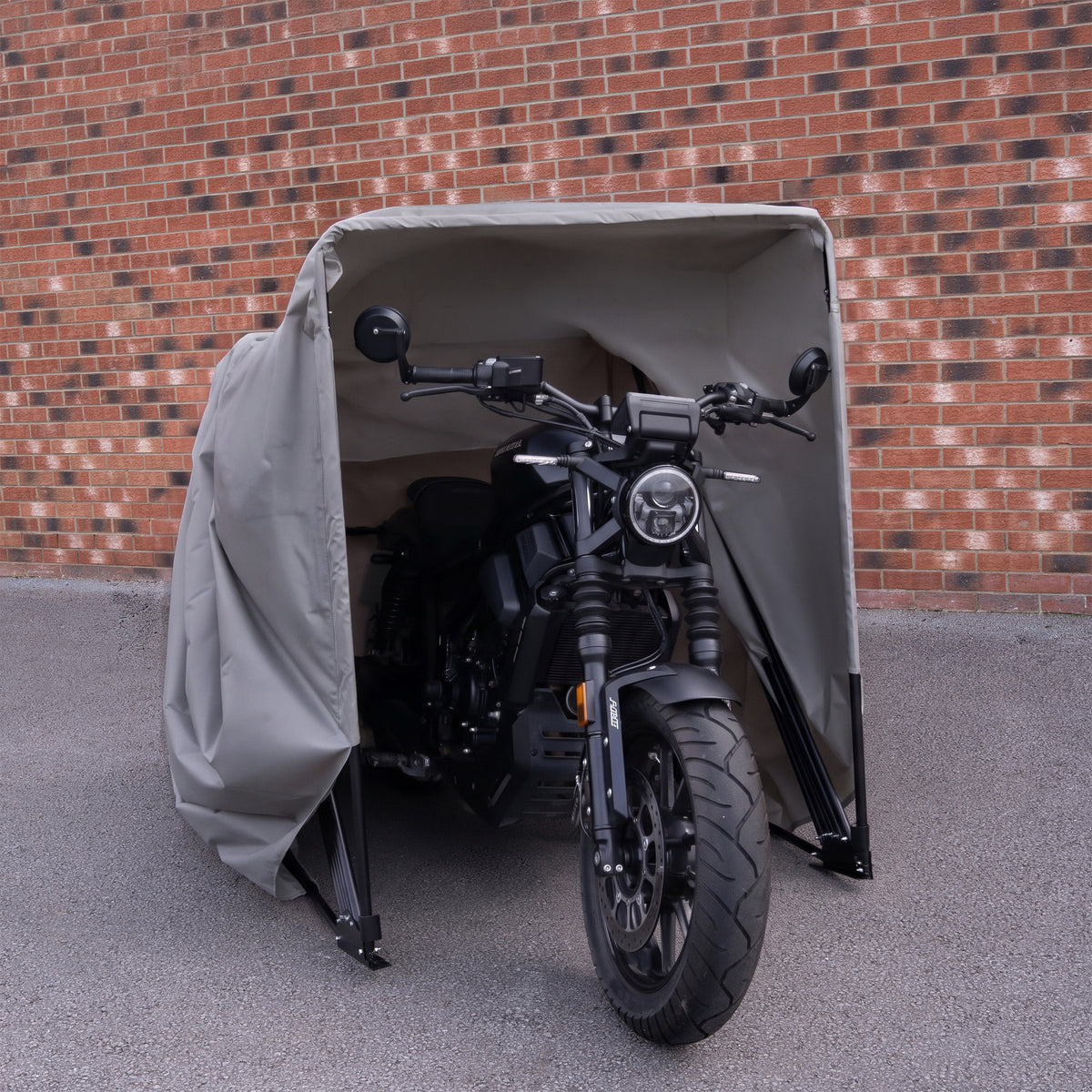 Zwarte motorfiets met een robuuste uitstraling, beschermd door een grijze, waterdichte hoes in een moderne, industriële omgeving