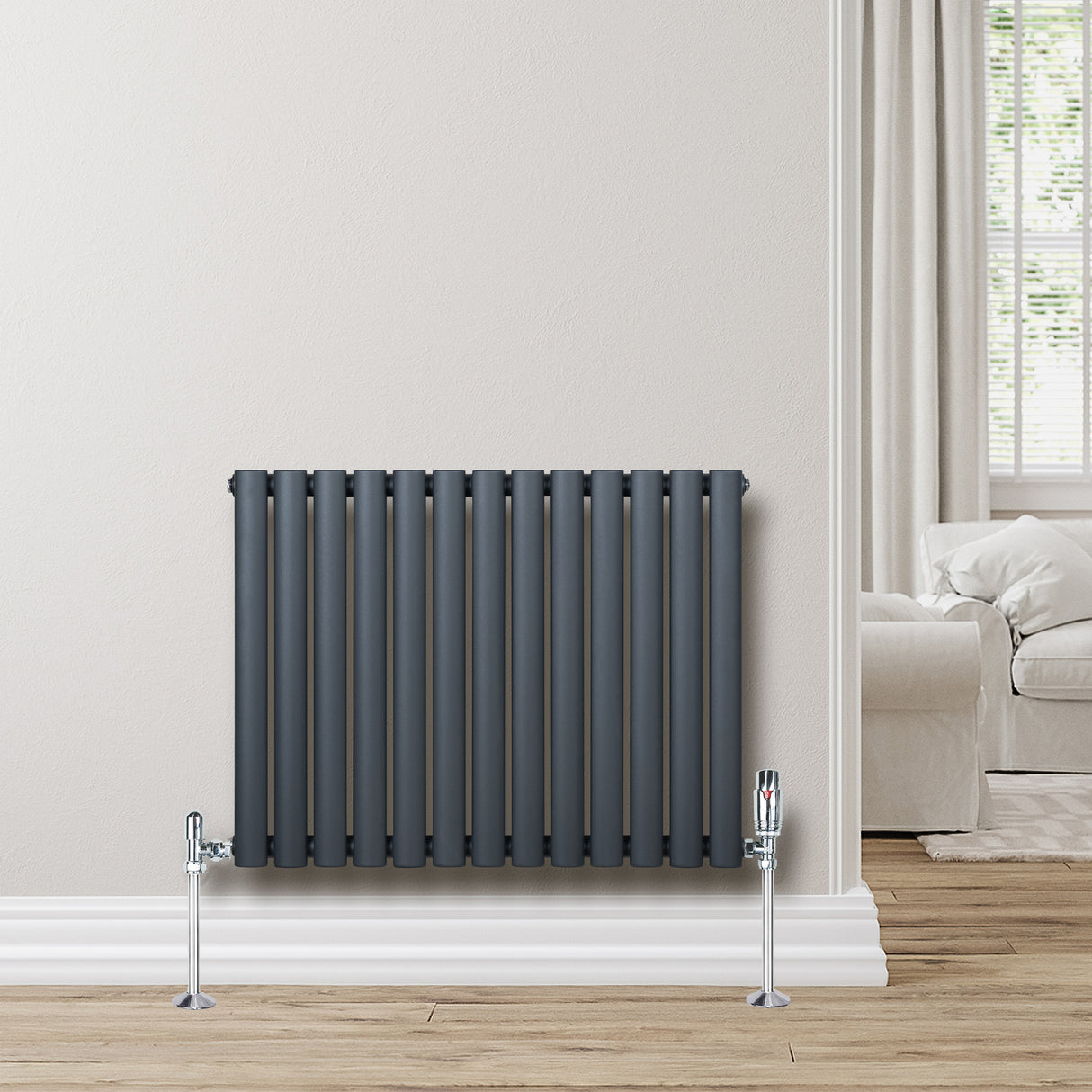 Ovale design radiator in antraciet grijs met één kolom, inclusief haakse thermostaatkraan, geplaatst tegen een lichte muur