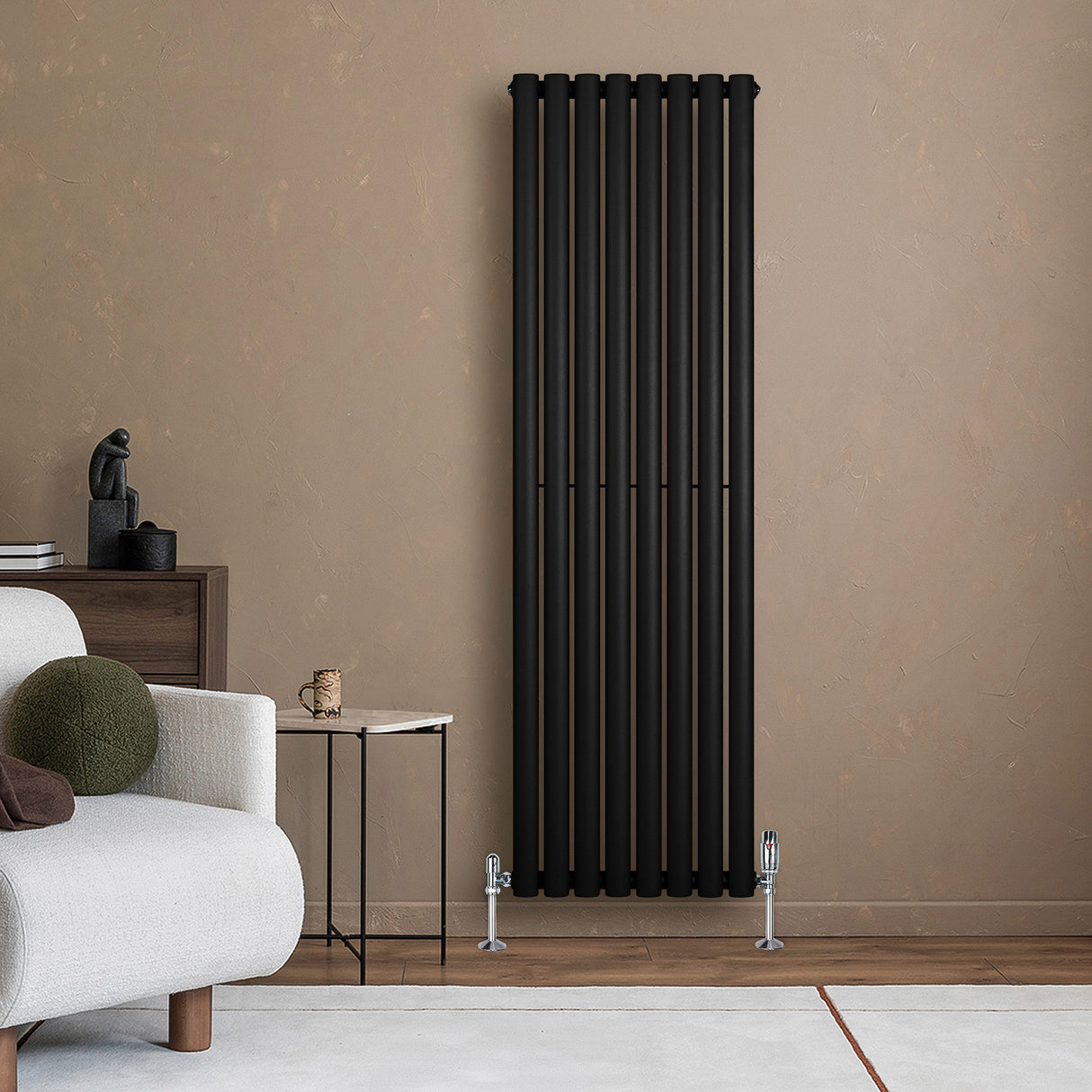 Ovale zwarte designradiator van 1600 mm x 480 mm met haakse thermostaatkraan, elegant geplaatst tegen een beige muur