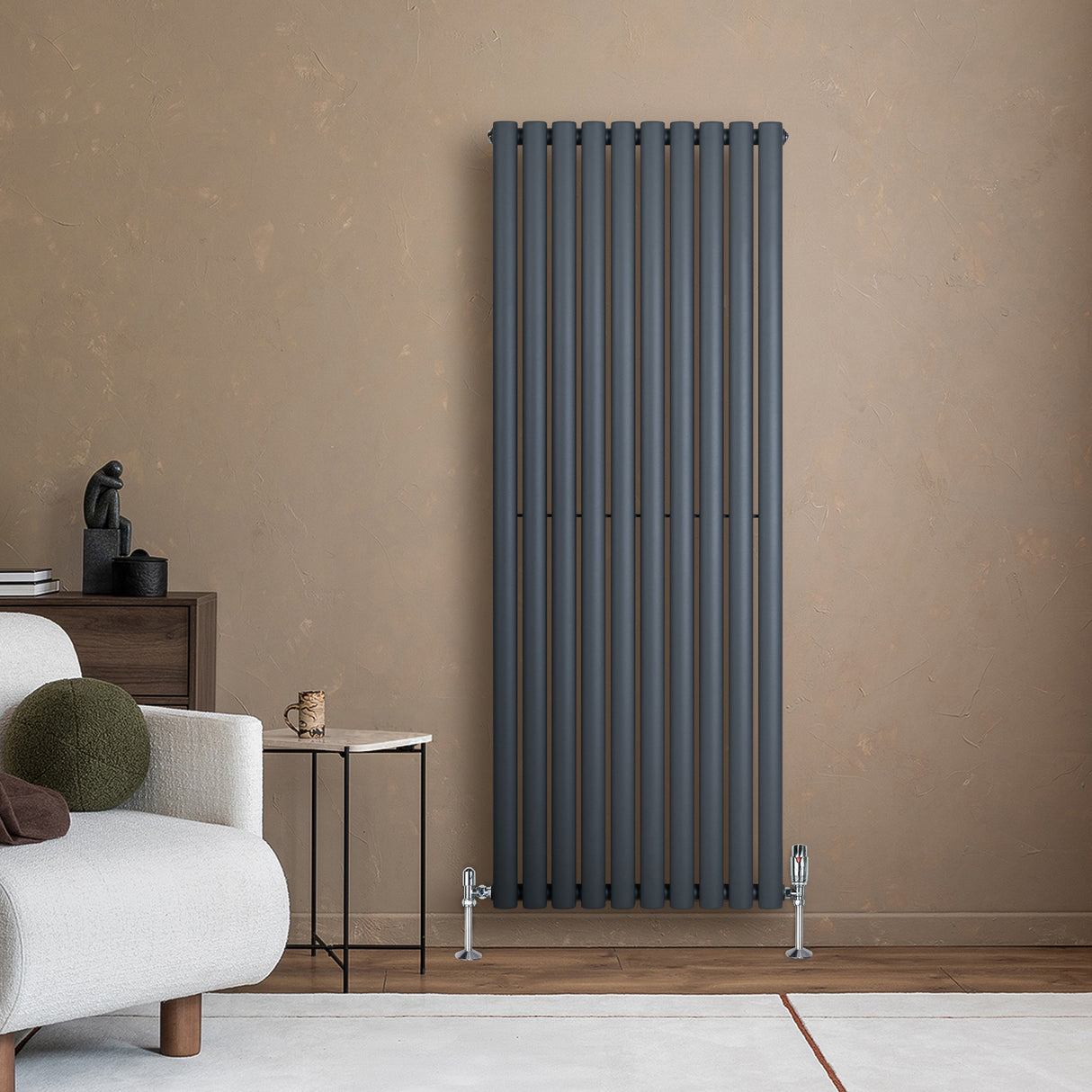 Ovale antraciet grijze design radiator met één kolom, geplaatst tegen een warme, neutrale muur in een moderne woonkamer