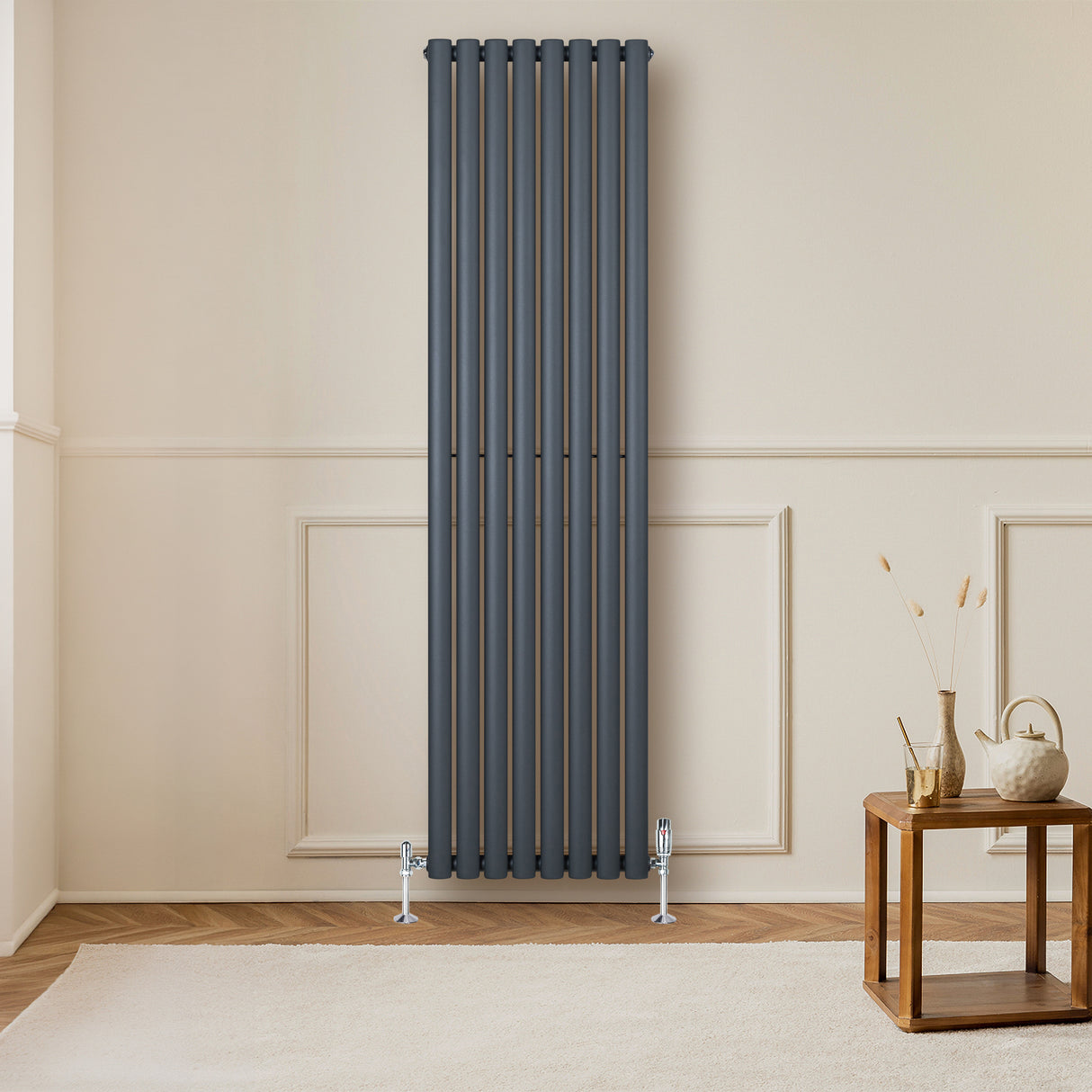 Ovale antraciet grijze radiator met één kolom, 1800 mm x 480 mm, inclusief haakse thermostaatkraan, tegen een lichte muur