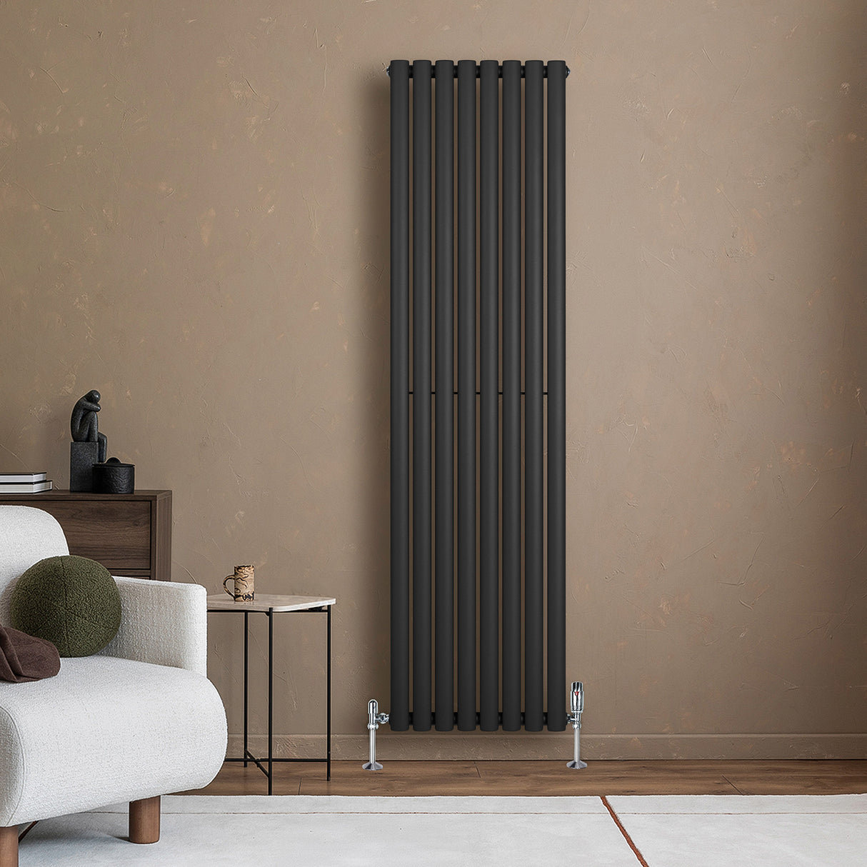 Ovale zwarte designradiator van 1800 mm x 480 mm met haakse thermostaatkraan, geplaatst tegen een beige muur in een moderne woonkamer