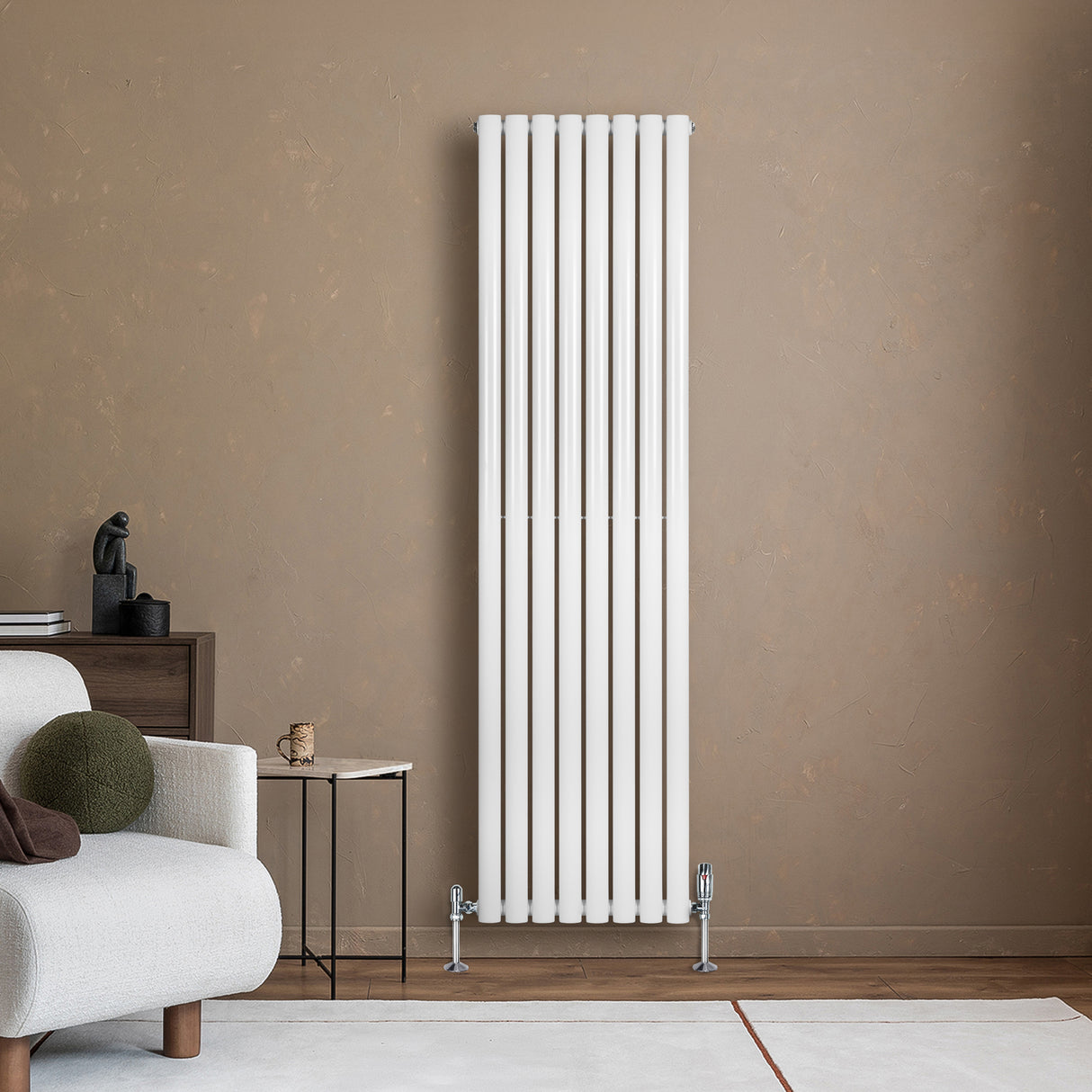 Ovale witte designradiator van 1800 mm x 480 mm met een haakse thermostaatkraan, geplaatst tegen een warme, neutrale muur