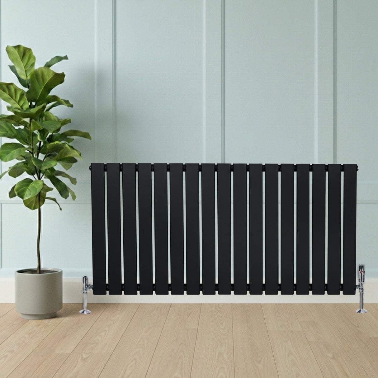 Zwart designradiator met vlakke panelen en haakse thermostaatkraan, geplaatst tegen een lichte wand met een groene plant ernaast