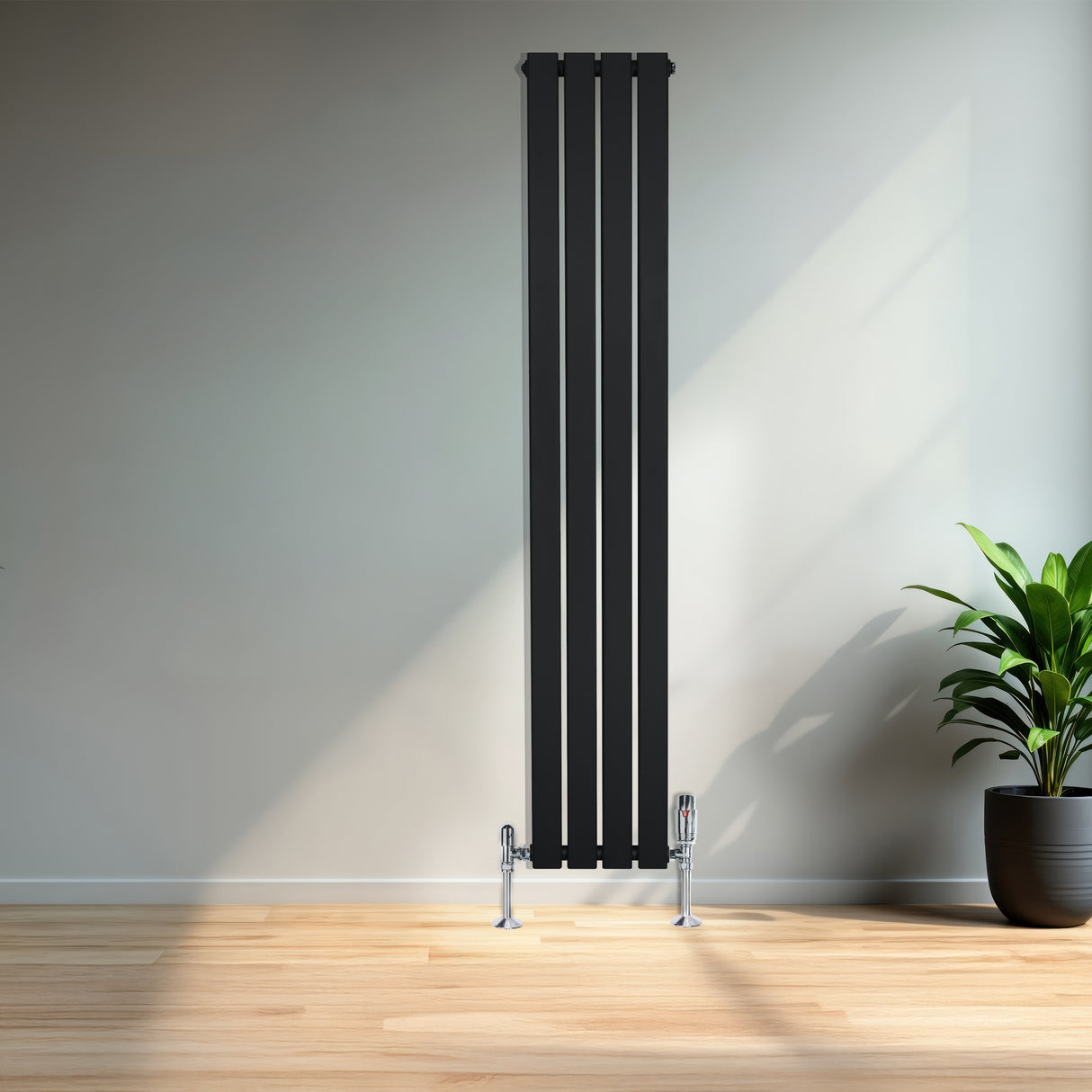 Zwarte designradiator met vlakke panelen en haakse thermostaatkraan, geplaatst tegen een lichte muur met een groene plant ernaast