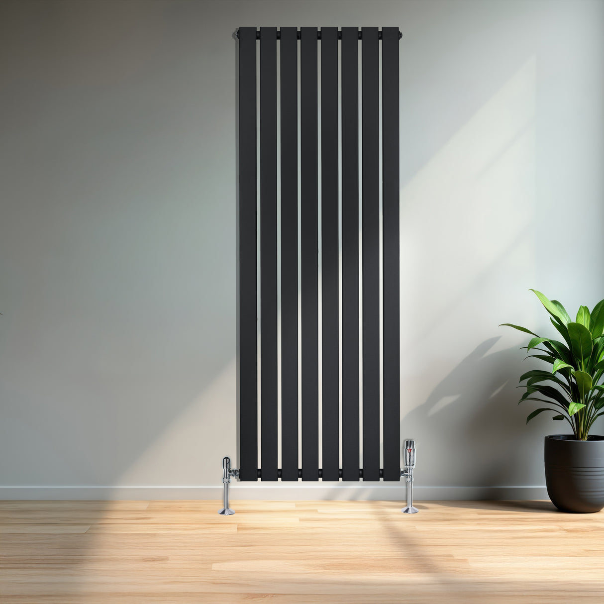 Zwarte designradiator met vlakke panelen en haakse thermostaatkraan, geplaatst tegen een lichte muur met een groene plant ernaast