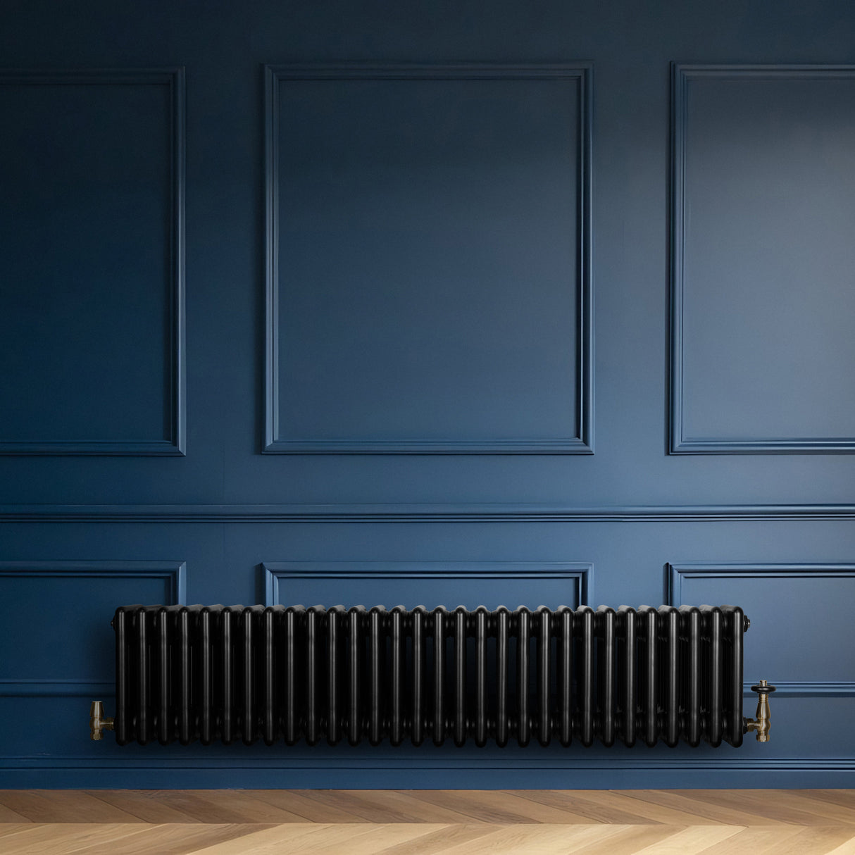 Zwarte traditionele 4-kolom radiator van 300 x 1370 mm met haakse thermostaatkraan, geplaatst tegen een blauwe wand