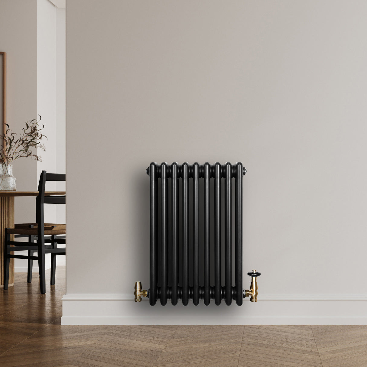 Traditionele zwarte 4-kolom radiator van 600 x 425 mm met een haakse thermostaatkraan, geplaatst tegen een lichte muur