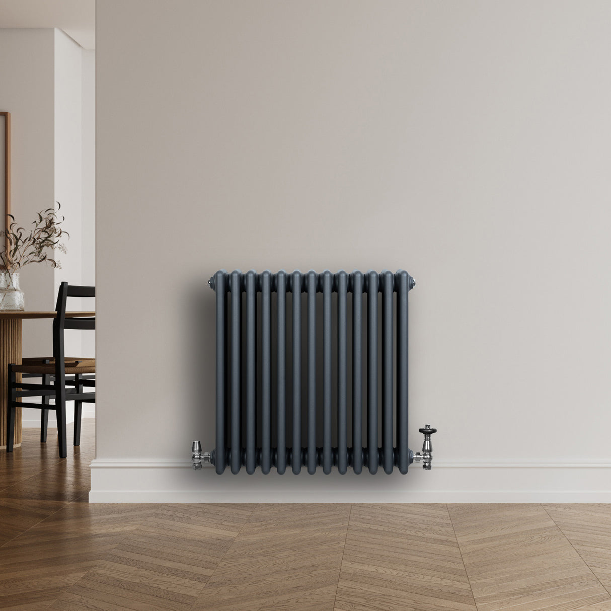 Traditionele antraciet grijze 4-kolom radiator met haakse thermostaatkraan, geplaatst tegen een lichte muur in een moderne ruimte