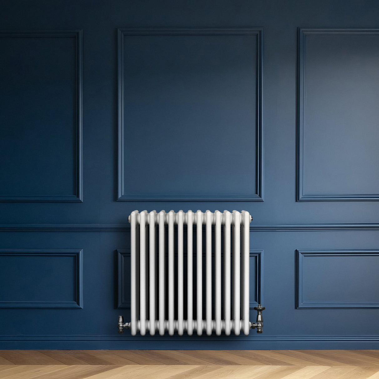 Traditionele witte 4-kolom radiator van 600 x 605 mm met haakse thermostaatkraan, geplaatst tegen een donkerblauwe wand