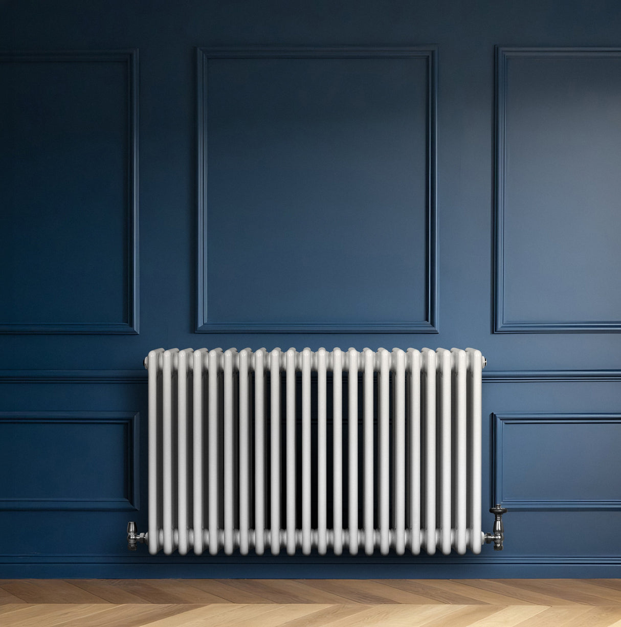 Traditionele witte 4-kolom radiator van 600 x 1010 mm met haakse thermostaatkraan, geplaatst tegen een donkerblauwe muur