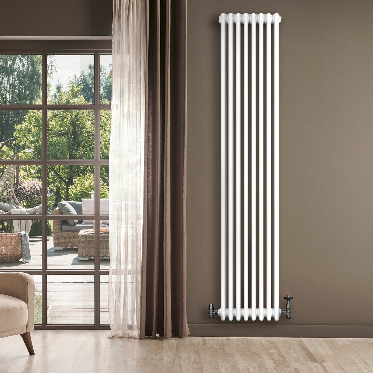 Traditionele witte 4-kolom radiator van 1800 x 380 mm met haakse thermostaatkraan, geplaatst naast een grote raam met uitzicht op de tuin