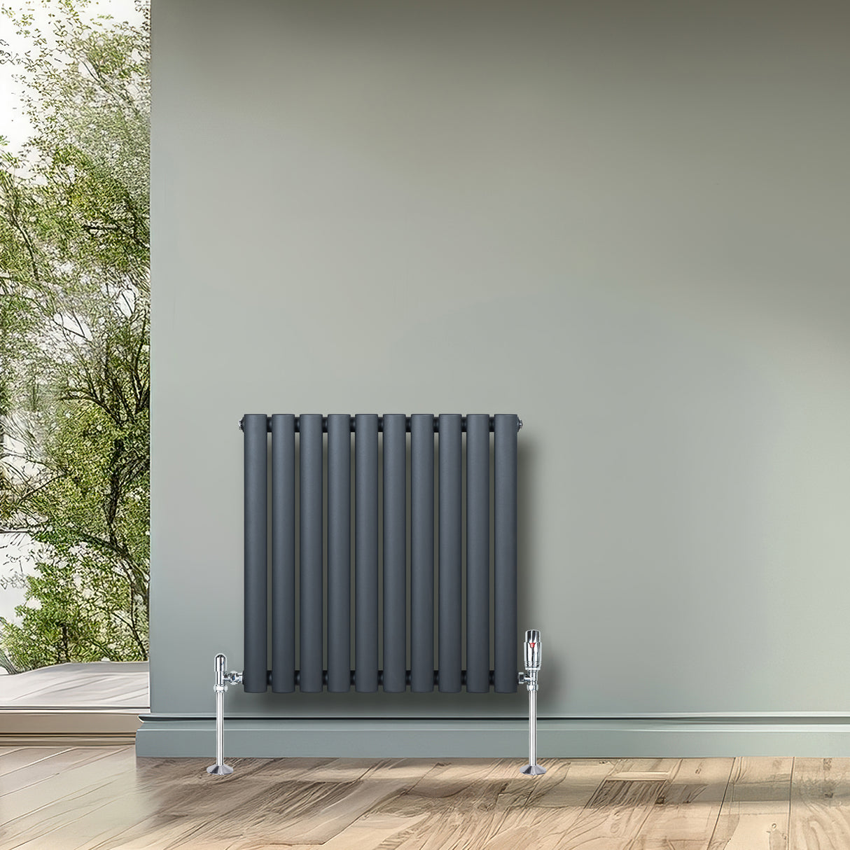 Ovale design radiator in antraciet grijs met één kolom, 600 mm x 600 mm, inclusief haakse thermostaatkraan, tegen een groene muur