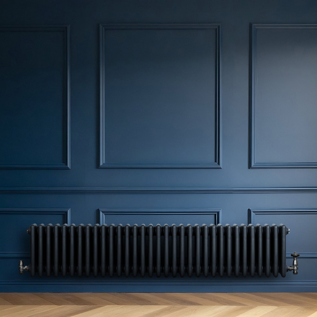 Traditionele 4-kolom radiator in antracietgrijs, met een glanzende afwerking, geplaatst tegen een diepblauwe wand