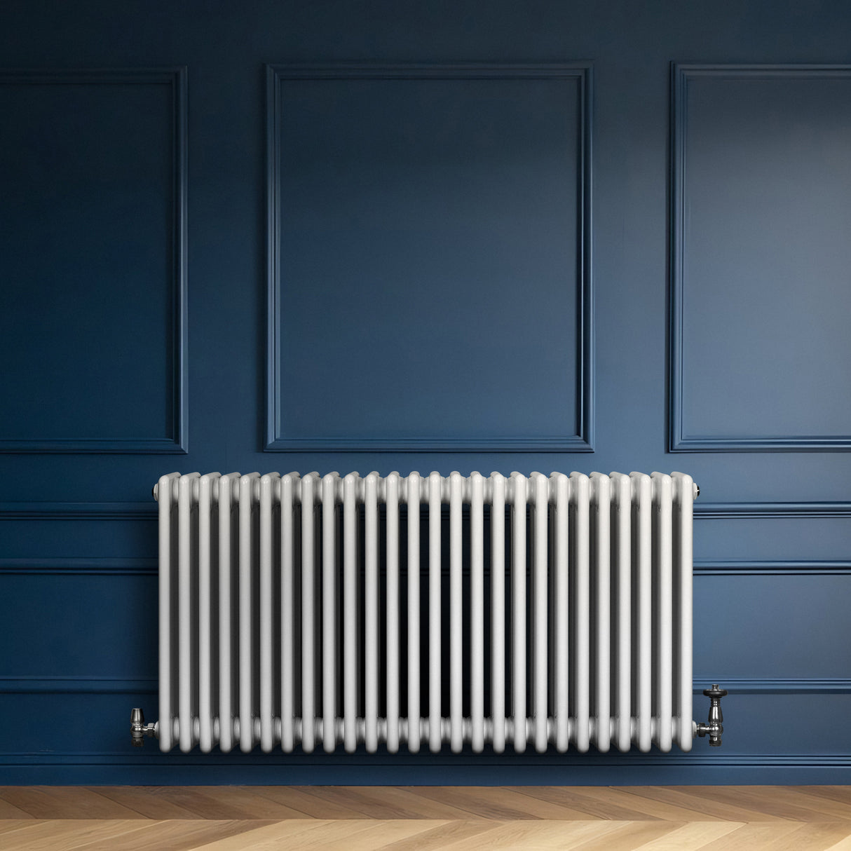 Traditionele witte 4-kolom radiator van 600 x 1190 mm, geplaatst tegen een donkerblauwe wand met een houten vloer eronder