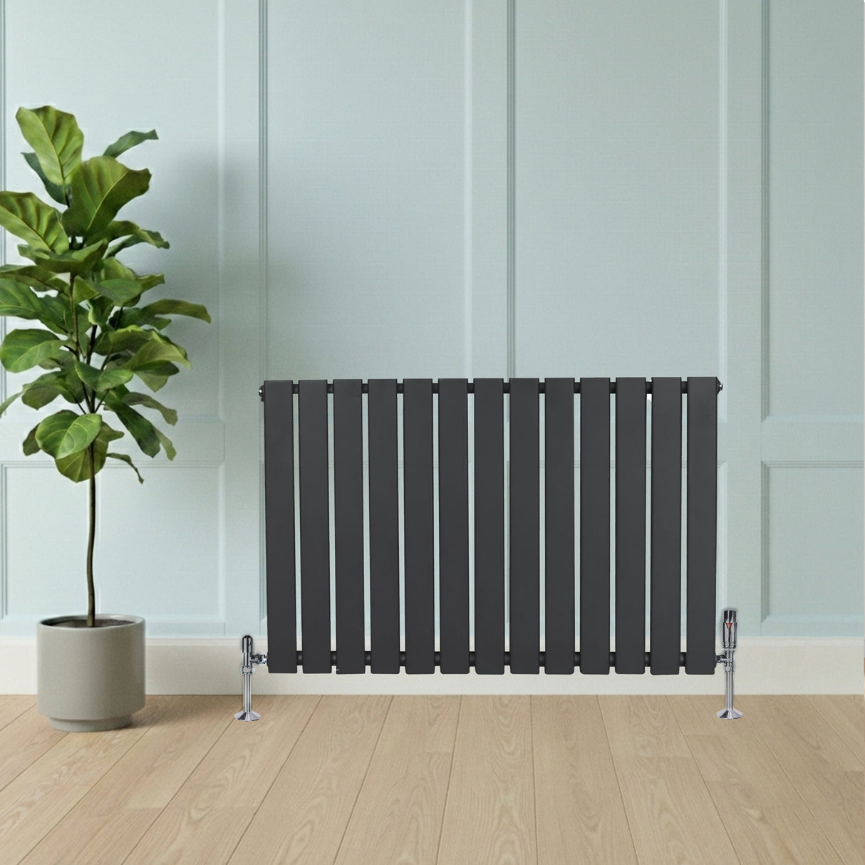 Design radiator met vlakke panelen in antraciet grijs, 1 kolom, 600 x 910mm, geplaatst tegen een lichte wand met een groene plant ernaast