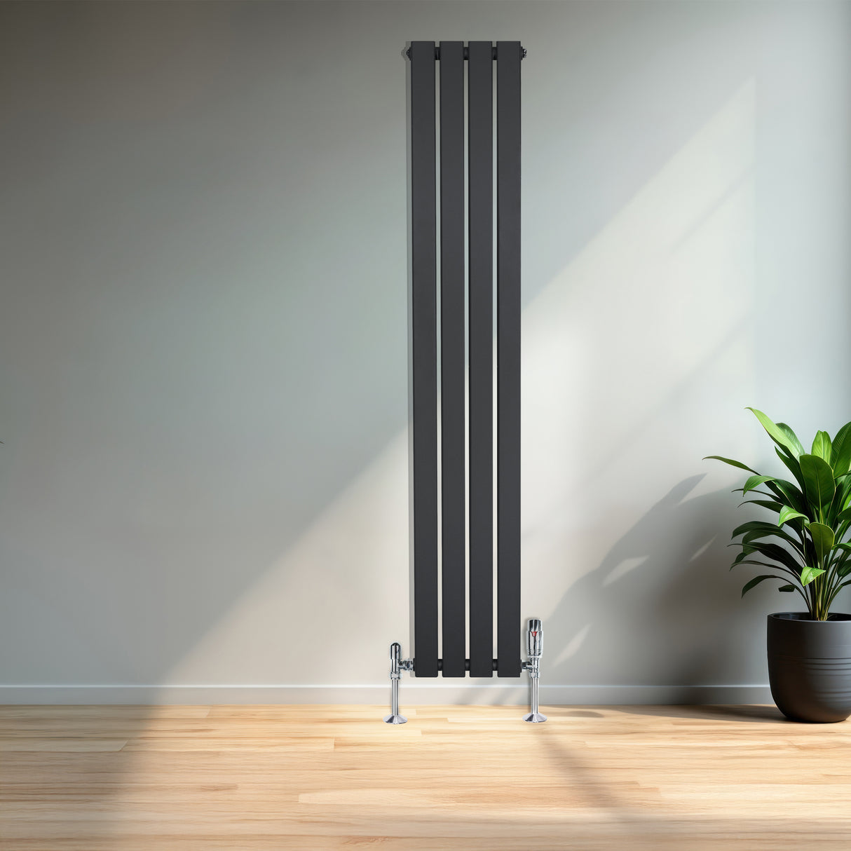 Design radiator met vlakke panelen in antraciet grijs, 1 kolom, 1600 x 280mm, geplaatst tegen een lichte muur met een groene plant ernaast