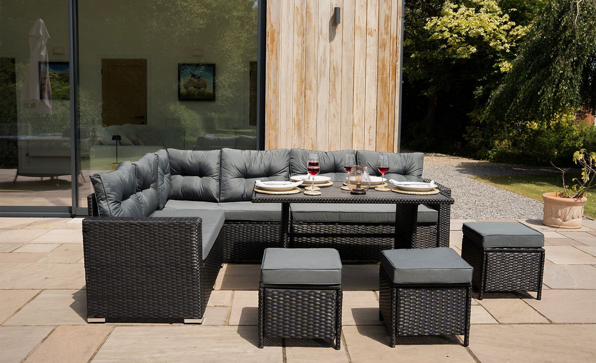 Moderne tuinset met een grijze stoffen bekleding, wicker meubels en een tafel, perfect voor buiten dineren en ontspanning