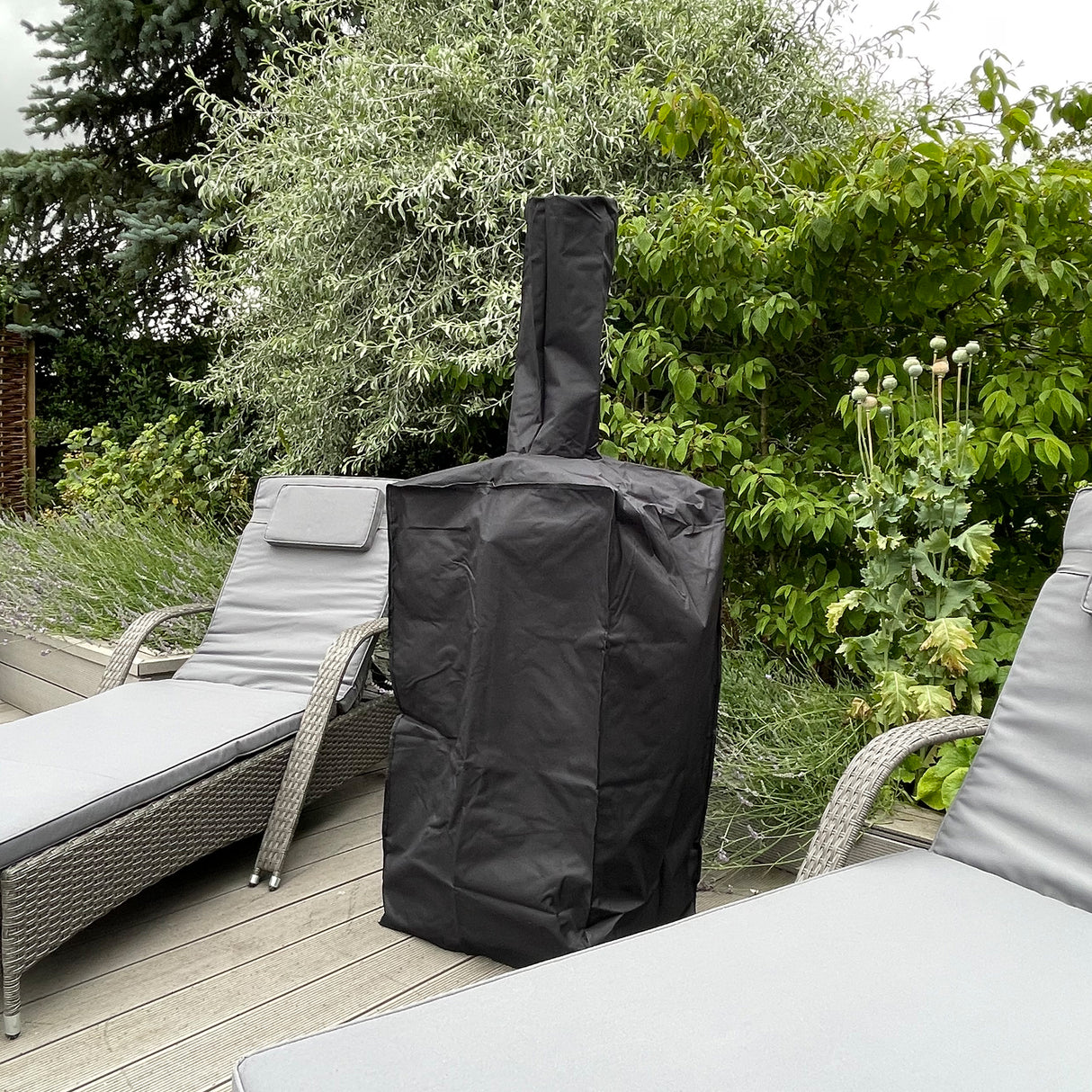 Zwarte hoes voor de KuKoo buiten pizzaoven, perfect passend en waterdicht, geplaatst op een houten terras tussen loungestoelen en groen