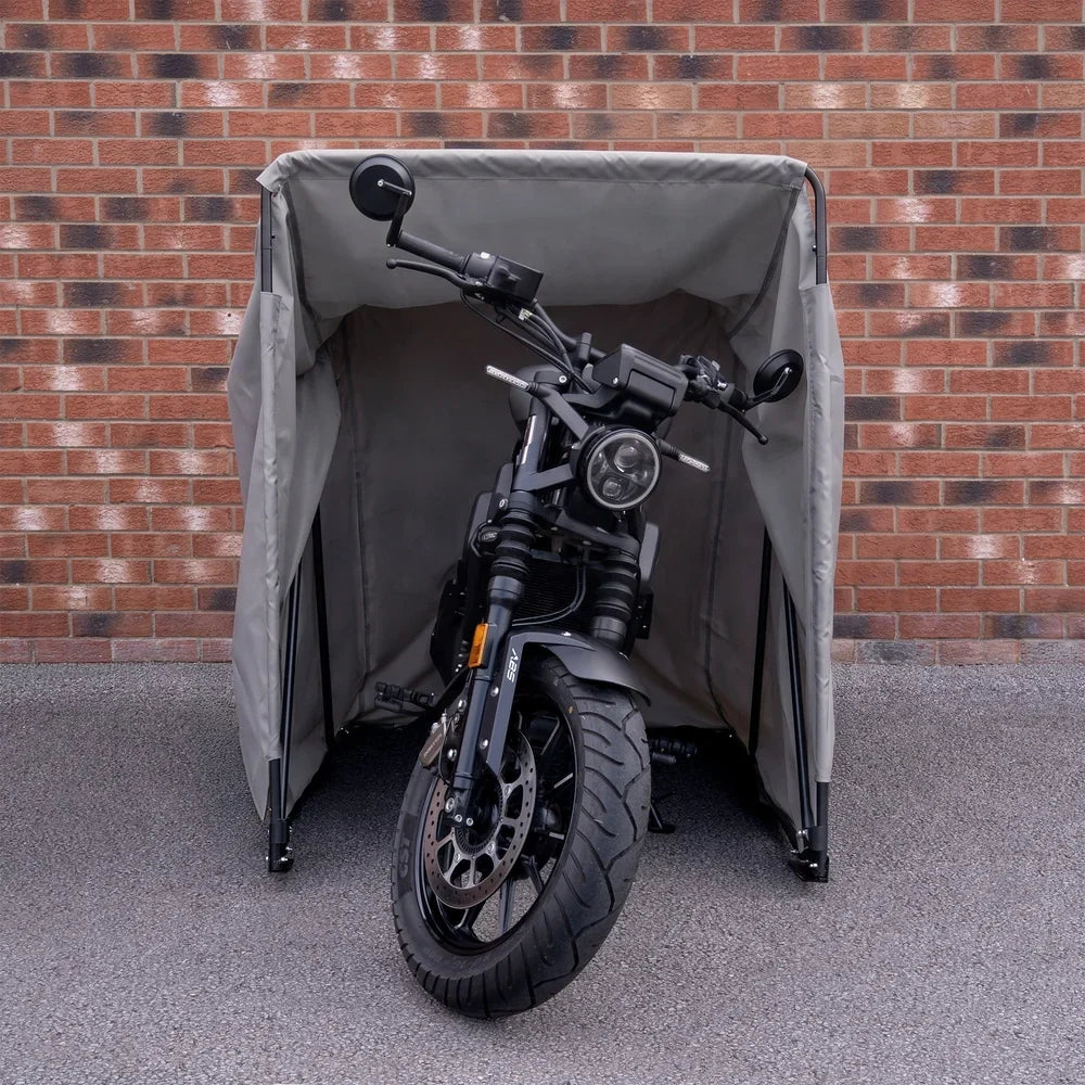 Zwarte motor onder een grijze motortent, veilig en waterdicht, met een bakstenen muur op de achtergrond en een gladde ondergrond