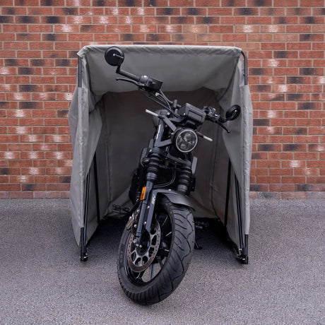 Zwarte motor onder een grijze motortent, veilig en waterdicht, met een bakstenen muur op de achtergrond en een gladde ondergrond