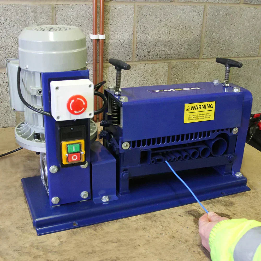 Robuuste blauwe draadstripmachine met motor, knoppen en waarschuwingslabel, geplaatst op een houten werkblad in een industriële omgeving