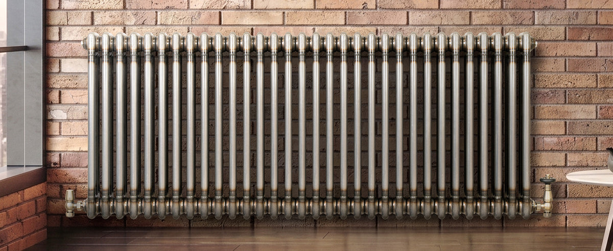 Stalen radiator met een glanzende afwerking, geplaatst tegen een bakstenen muur, met een industrieel ontwerp en rechte lijnen