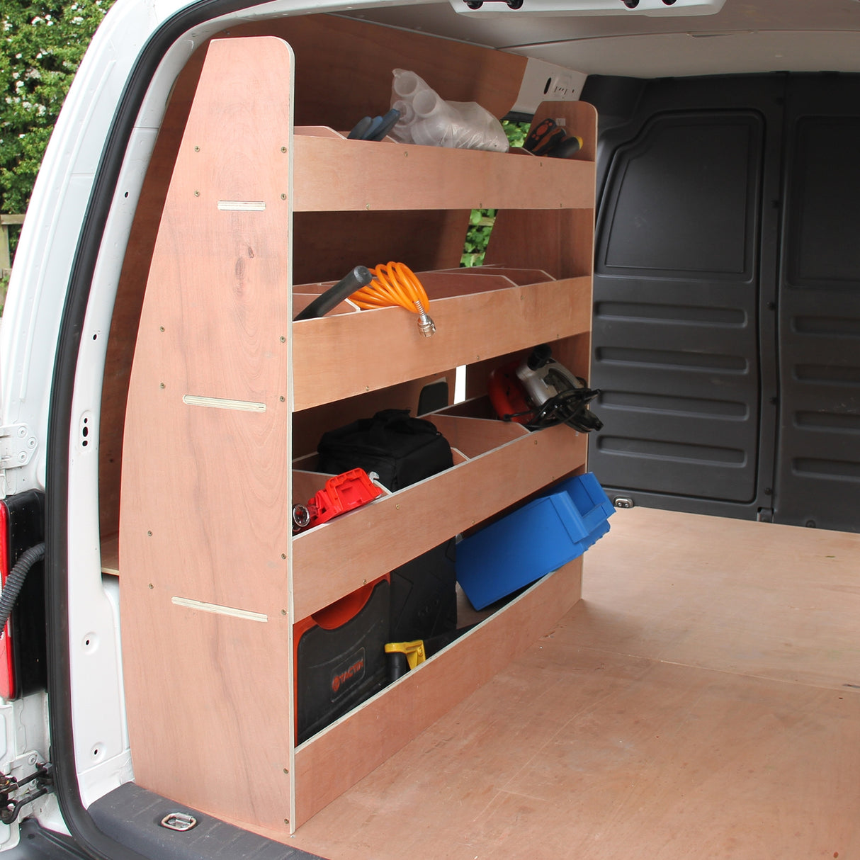 Antraciet bestelwagenbekleding met houten rek, drie open schappen gevuld met gereedschap en accessoires in een VW Caddy