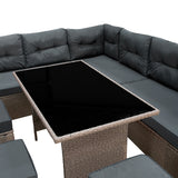 Grijze polyrattan hoekmeubelset met comfortabele kussens en een zwart glazen tafelblad, perfect voor buitengebruik