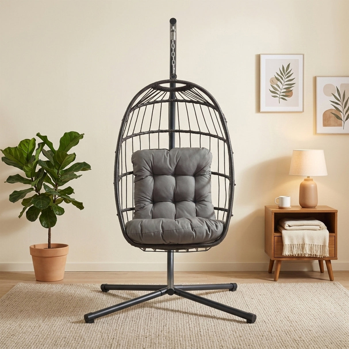 Zwarte rotan hangstoel met een comfortabele grijze kussen, stevig metalen frame en een moderne uitstraling in een lichte kamer