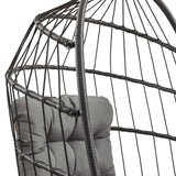 Zwart rotan hangstoel met een moderne, open structuur en een comfortabele grijze kussen voor extra zitcomfort