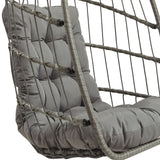 Grijze rotan hangstoel met een comfortabele, gestoffeerde kussen en een opengewerkt, gevlochten ontwerp voor een moderne uitstraling