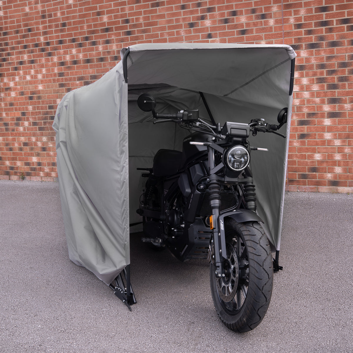 Zwarte motorfiets met een moderne uitstraling, beschermd door een grijze tent, geplaatst tegen een bakstenen muur