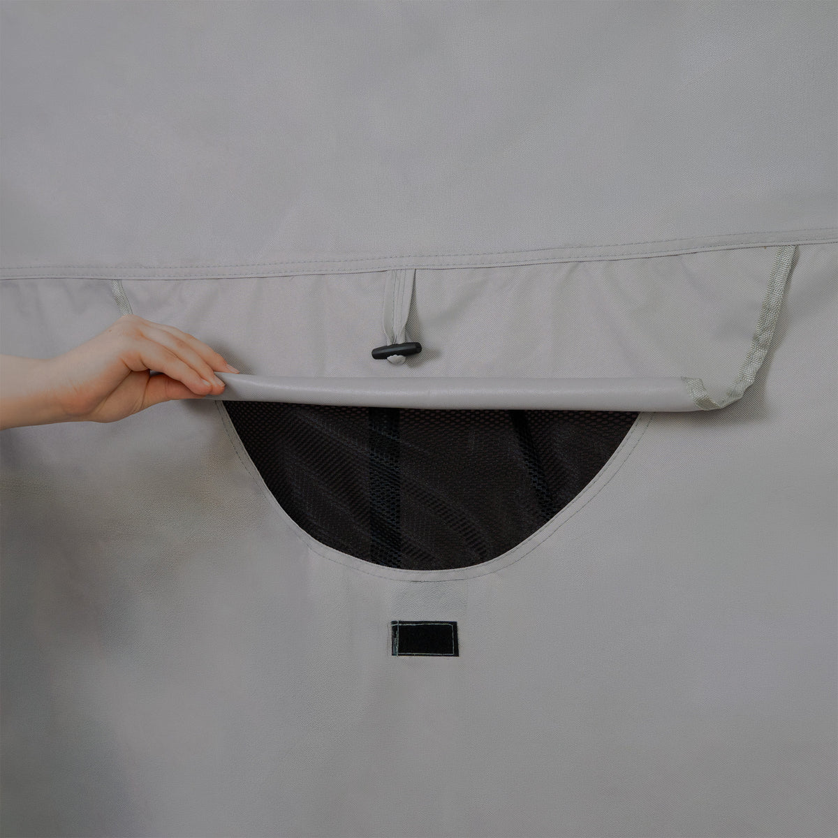 Grijze opbergzak met een hand die de bovenkant opent, onthullend een zwart gaasvak voor ventilatie en zichtbaarheid van inhoud