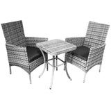 Twee stijlvolle wicker stoelen met kussens en een bijpassende tafel, allemaal in grijstinten met een moderne uitstraling
