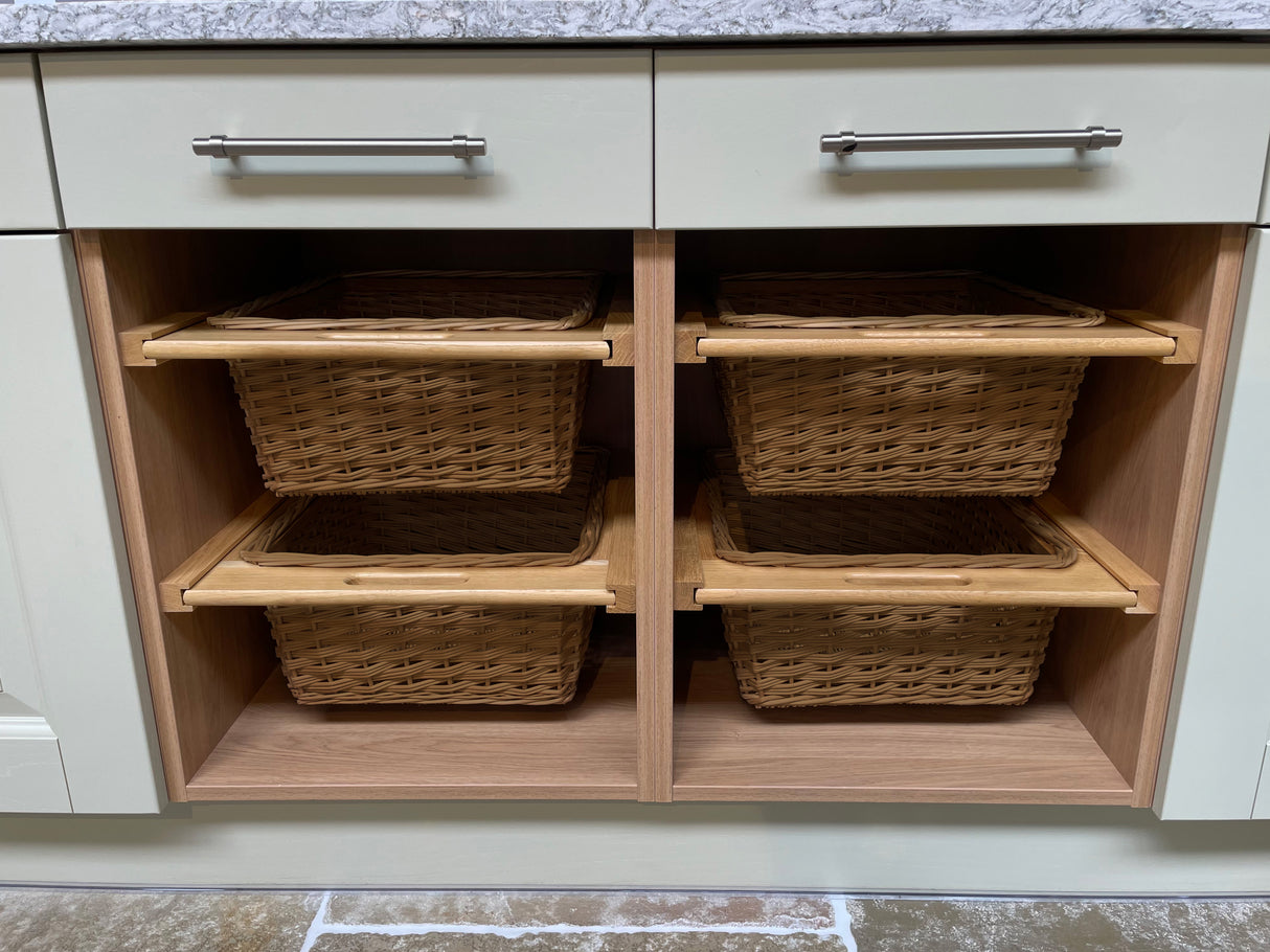 Uittrekbare rieten manden in een kast, met een natuurlijke kleur en houten handvatten, perfect voor opbergruimte en organisatie