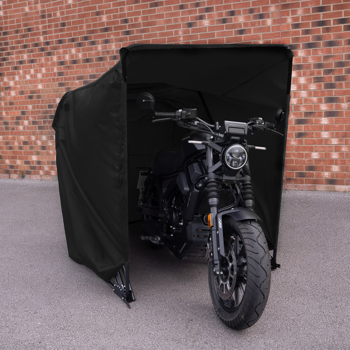 Zwart motorafdekzeil met een motorfiets eronder, geplaatst tegen een bakstenen muur, biedt bescherming tegen weersinvloeden