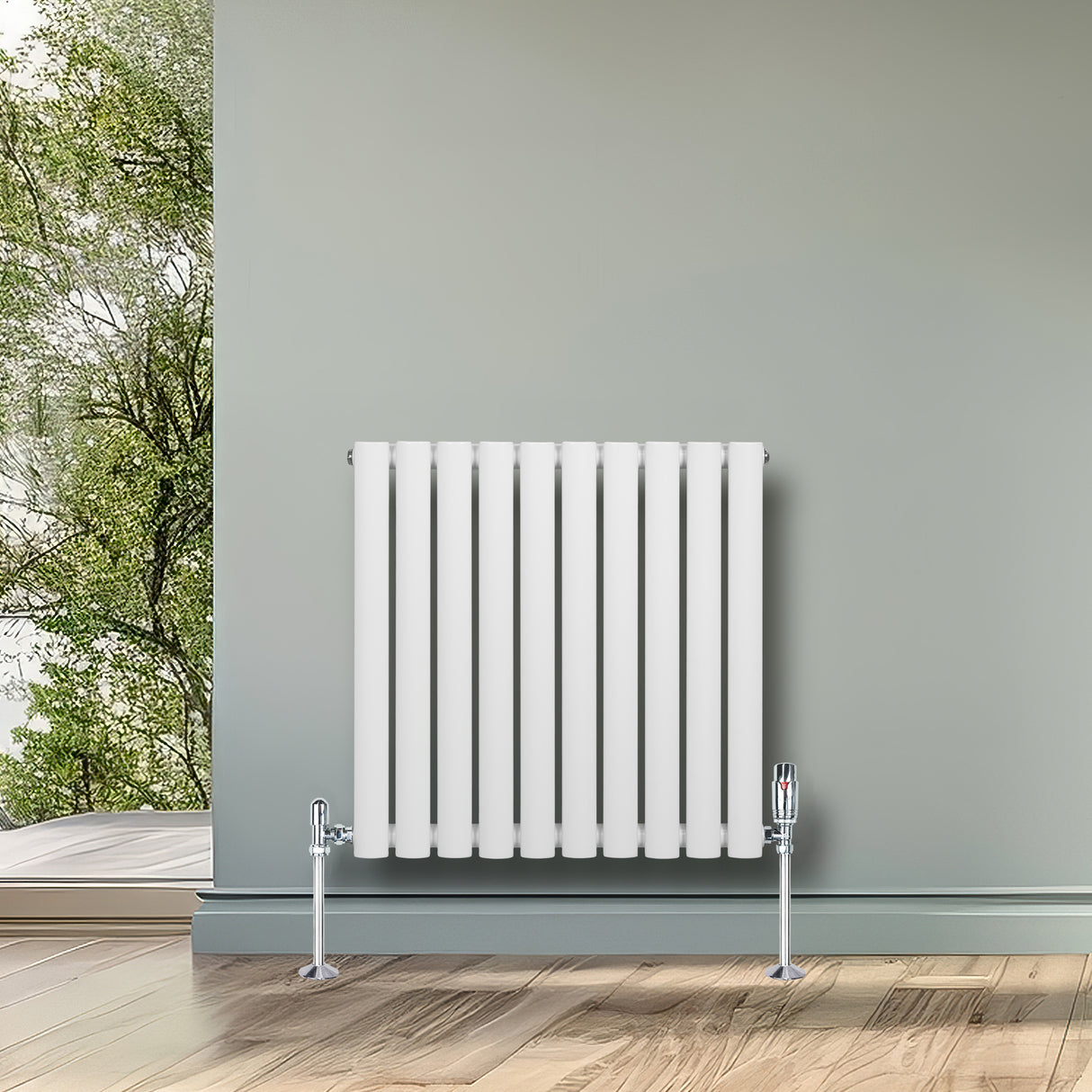 Ovale witte design radiator met één kolom, 600 mm x 600 mm, inclusief haakse thermostaatkraan, geplaatst tegen een groene muur