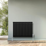 Ovale zwarte designradiator met één kolom, 600 mm x 780 mm, inclusief haakse thermostaatkraan, tegen een lichte muur