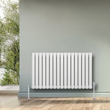 Ovale witte designradiator met één kolom, 600 mm x 1020 mm, geplaatst tegen een groene muur, inclusief haakse thermostaatkraan