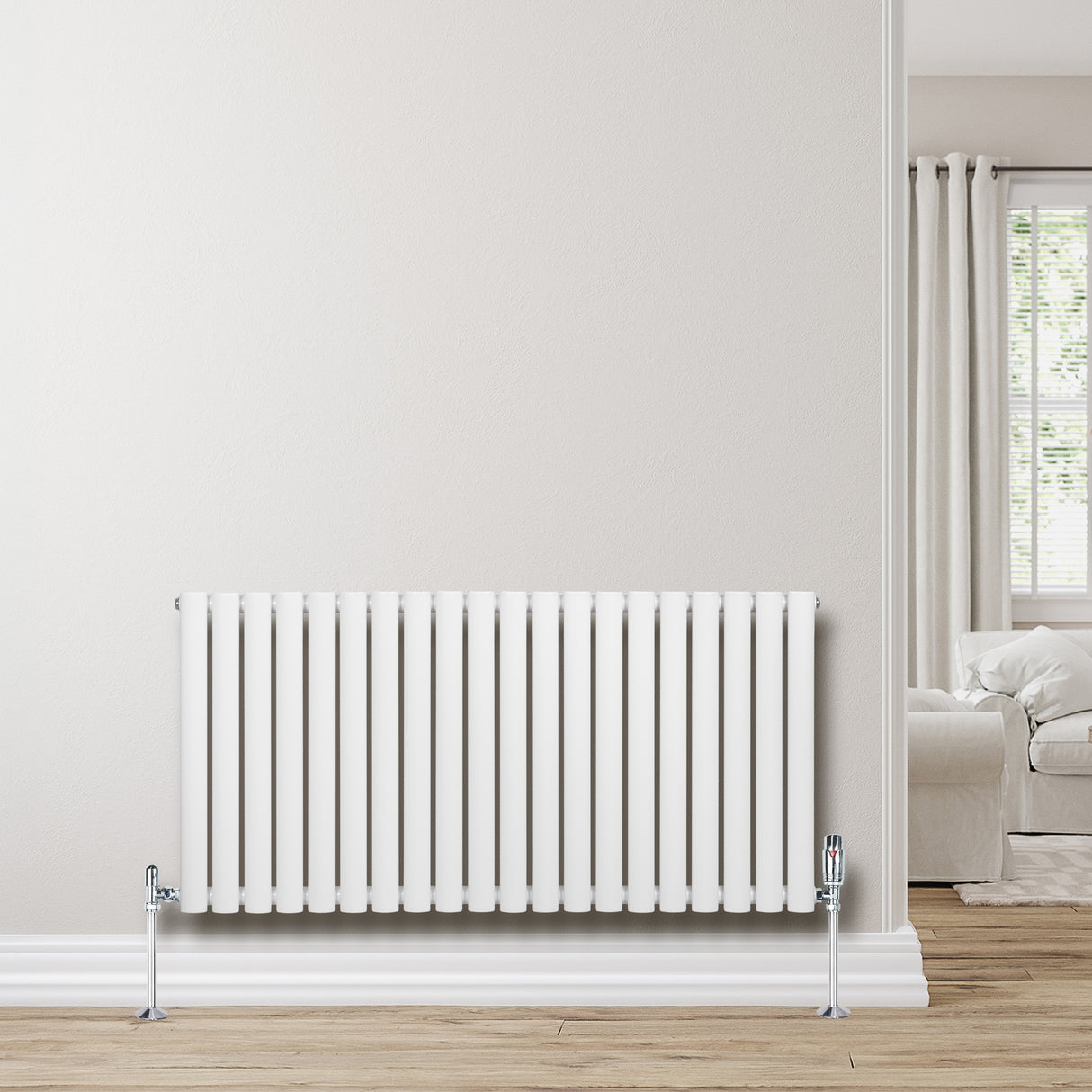 Ovale witte design radiator met één kolom, 600 mm x 1200 mm, inclusief haakse thermostaatkraan, geplaatst tegen een lichte muur