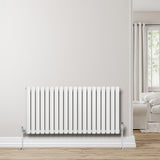 Ovale witte design radiator met één kolom, 600 mm x 1200 mm, inclusief haakse thermostaatkraan, geplaatst tegen een lichte muur