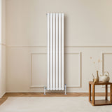 Ovale witte design radiator met één kolom, 1600 mm x 360 mm, inclusief haakse thermostaatkraan, geplaatst tegen een lichte wand