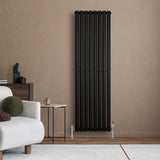 Ovale zwarte designradiator van 1600 mm x 480 mm met haakse thermostaatkraan, elegant geplaatst tegen een beige muur