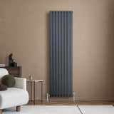 Ovale design radiator in antraciet grijs, 1800 mm x 480 mm, met haakse thermostaatkraan, geplaatst tegen een warme muur