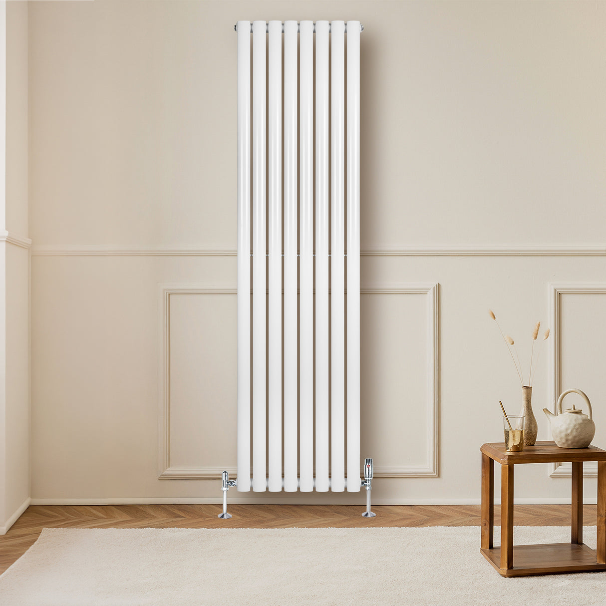 Ovale witte design radiator van 1800 mm x 480 mm met haakse thermostaatkraan, geplaatst tegen een lichte muur in een moderne kamer