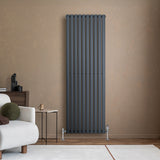 Ovale antraciet grijze design radiator met één kolom, 1800 mm x 600 mm, inclusief haakse thermostaatkraan, tegen een warme muur