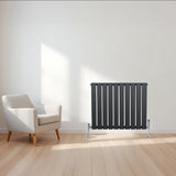 Design radiator met vlakke panelen in antraciet grijs, 600 x 700mm, geplaatst naast een moderne witte stoel op een houten vloer